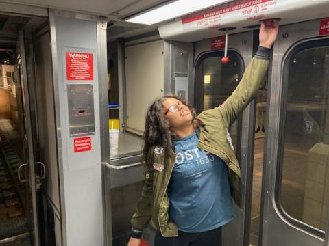 A passenger pulling down the red door lever on the train side door during the HRV Evacuation Safety Training.