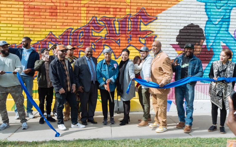 Buckeye-Woodhill community member, Marilyn Burns cuts ribbon for the “Elevate the East” mural, surrounded by GM and CEO of GCRTA India Birdsong Terry, Jeff Patterson, CEO & Safety Directory of CMHA, Cleveland City Council President Blaine Griffin, and the LAND studio artist who created it. 