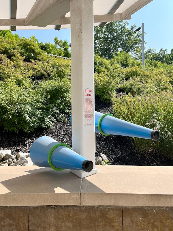 The colorful cones mounted on poles passed here are actually pieces of art. The cylinders are meant to resemble kaleidoscopes. Look into them and see either a scene from the industrial past of the neighborhood or one of the educational institutions present in the area. The words below the cylinders relate to the scene inside them. The red and orange cones illustrate industry while the blue and green relate to education. Take a minute and take a peek!