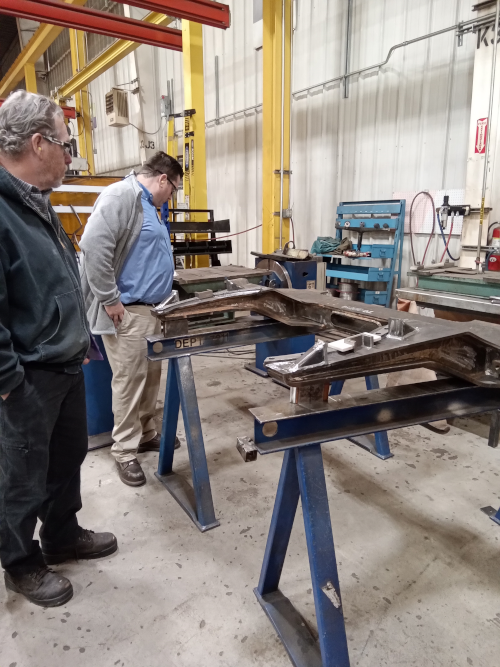 Kenneth Bisson (QA Manager, left) and Casey Blaze (RCRP Deputy Project Manager, right) examine one of the girders being fabricated—a structural member for the car frame.